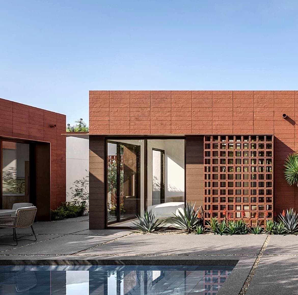 Fachada de casa con muro de cobogó terracota junto a la piscina